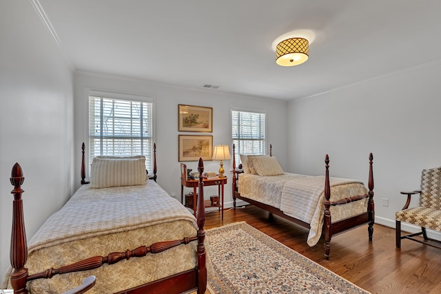 bedroom featuring dark wood-style floors, baseboards, visible vents, and ornamental molding