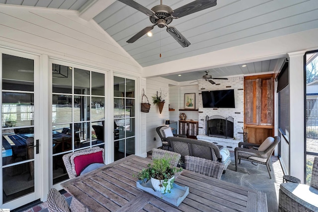 sunroom featuring lofted ceiling with beams, an outdoor brick fireplace, and a ceiling fan