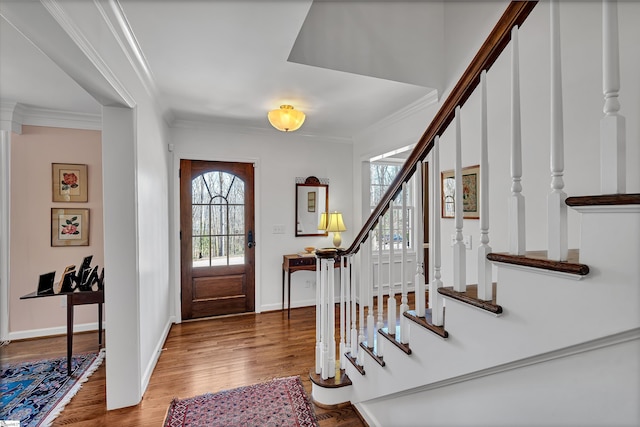 entrance foyer with ornamental molding, stairway, baseboards, and wood finished floors