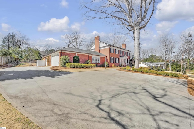 view of front of house with a garage, concrete driveway, brick siding, and fence