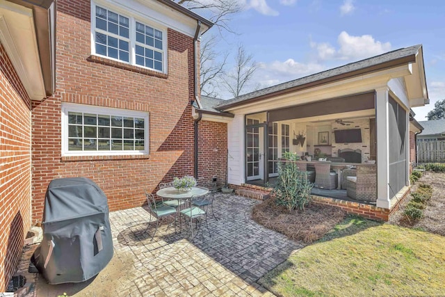 rear view of property with brick siding, a patio area, and a sunroom