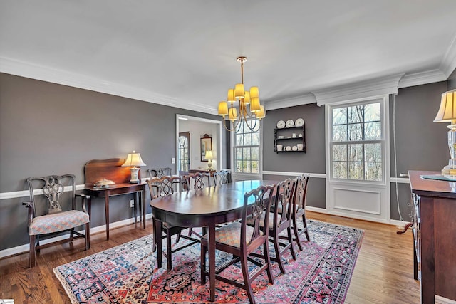 dining area featuring a notable chandelier, crown molding, baseboards, and wood finished floors