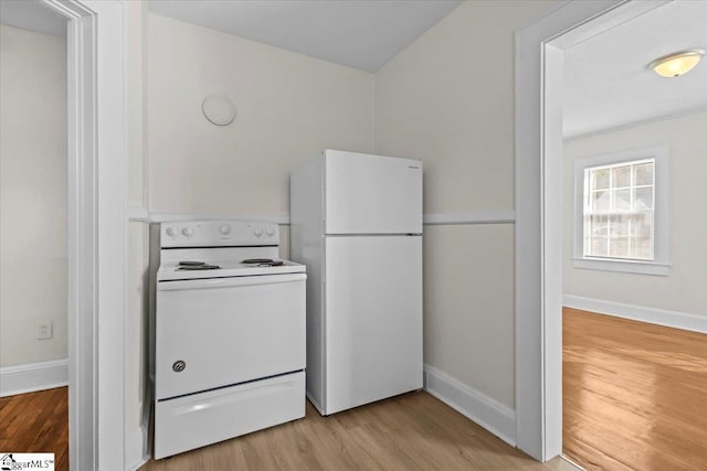 kitchen featuring white appliances, white cabinets, light wood-style flooring, and baseboards