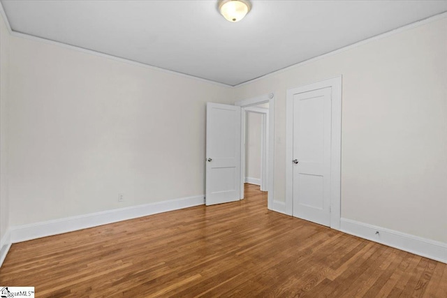 unfurnished room featuring crown molding, baseboards, and wood finished floors