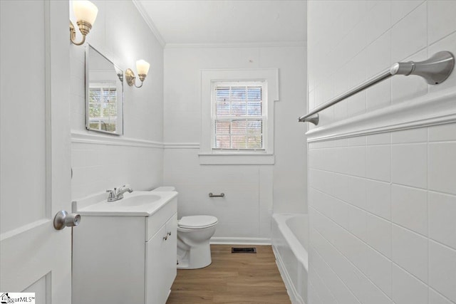 bathroom featuring visible vents, toilet, wood finished floors, vanity, and a bath