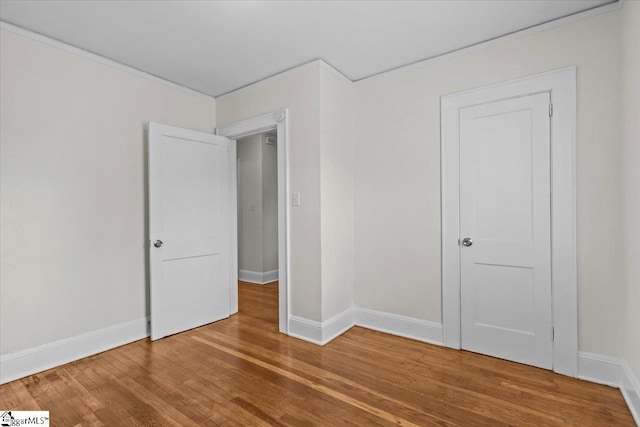 unfurnished bedroom with wood finished floors and baseboards