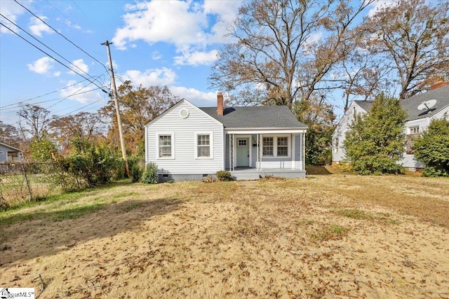 view of front of home featuring covered porch, fence, crawl space, a front lawn, and a chimney