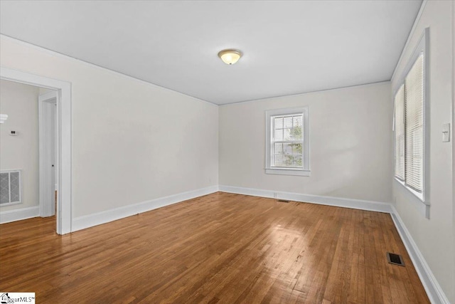 empty room featuring visible vents, baseboards, and wood finished floors