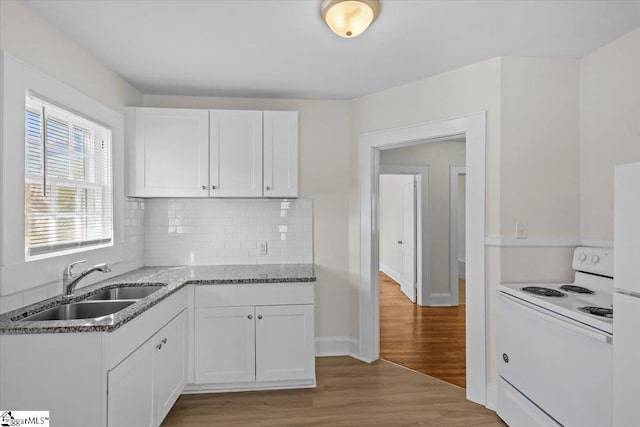 kitchen with white electric stove, light stone counters, light wood-style flooring, a sink, and white cabinetry