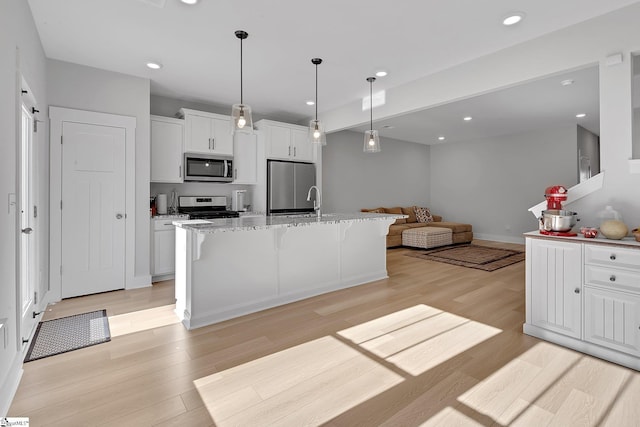 kitchen featuring stainless steel appliances, white cabinetry, and light wood-style floors