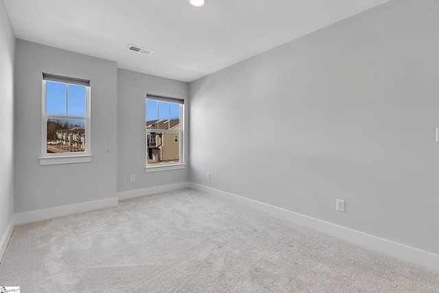 unfurnished room with carpet flooring, visible vents, and baseboards