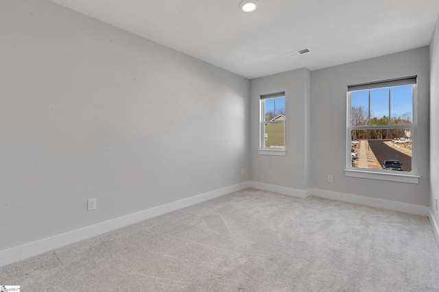 empty room with carpet floors, visible vents, and baseboards