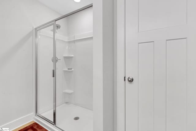 bathroom with a stall shower and baseboards