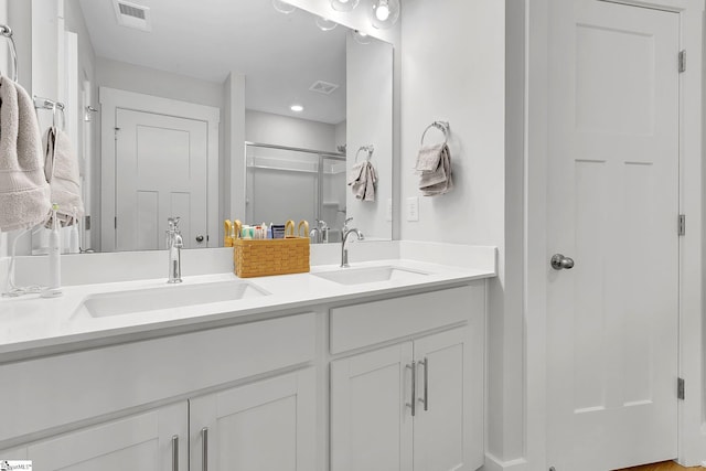 bathroom with a stall shower, visible vents, a sink, and double vanity