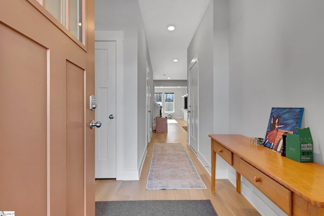 hall featuring baseboards, recessed lighting, and light wood-style floors