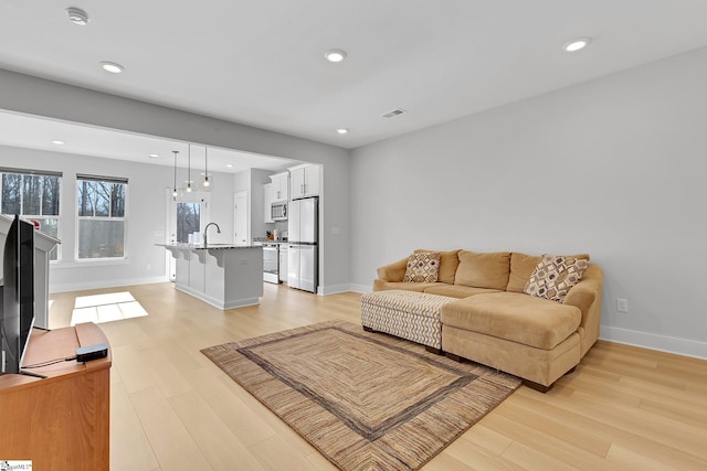 living area with baseboards, light wood-type flooring, visible vents, and recessed lighting