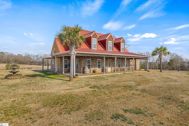 rear view of property featuring metal roof, stone siding, a standing seam roof, and a lawn