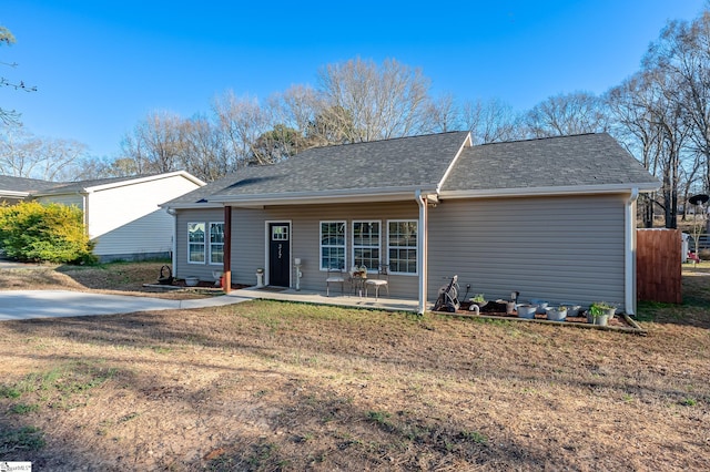 view of front of property featuring a shingled roof, a front yard, and a patio area