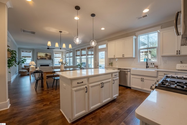 kitchen with crown molding, a fireplace, visible vents, a sink, and dishwasher