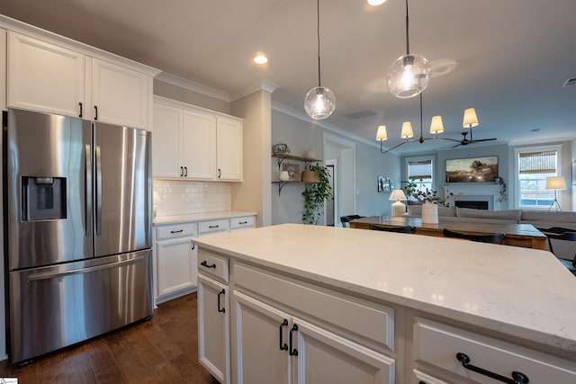 kitchen with a fireplace, tasteful backsplash, ornamental molding, open floor plan, and stainless steel fridge