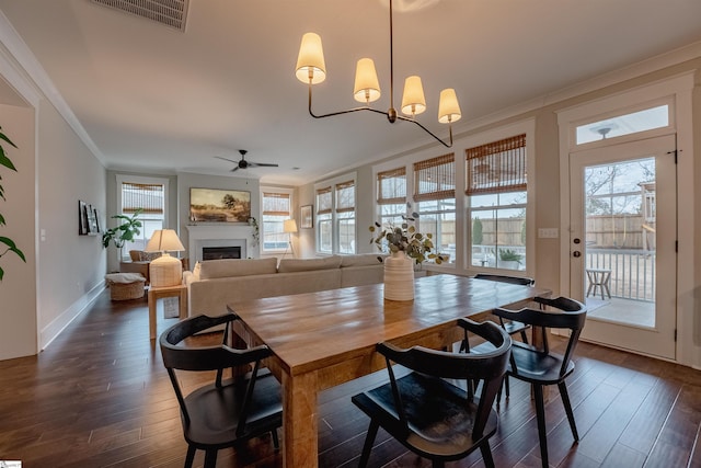 dining area featuring dark wood-style floors, a fireplace, visible vents, and crown molding