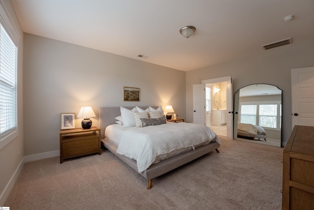 bedroom with light carpet, baseboards, visible vents, and connected bathroom