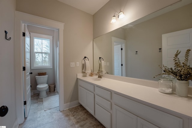 bathroom with toilet, vanity, and baseboards