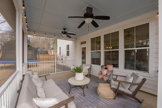 wooden deck with a trampoline, fence, and a ceiling fan