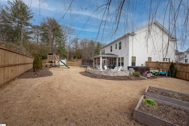 view of yard featuring a garden, a patio, a sunroom, a fenced backyard, and a playground