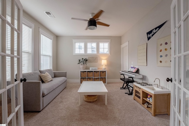 living area featuring french doors, light colored carpet, visible vents, ceiling fan, and baseboards