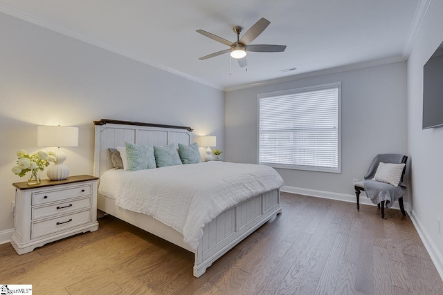 bedroom with visible vents, ornamental molding, a ceiling fan, wood finished floors, and baseboards