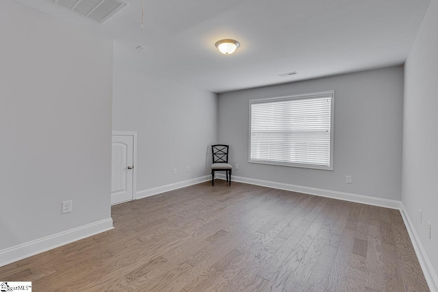 interior space featuring baseboards, attic access, visible vents, and wood finished floors