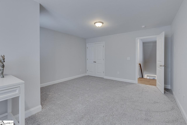 unfurnished bedroom with light carpet, a closet, and baseboards