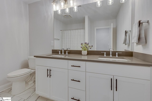 bathroom featuring marble finish floor, a sink, toilet, and double vanity