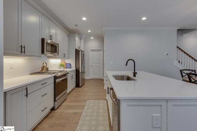 kitchen featuring tasteful backsplash, appliances with stainless steel finishes, ornamental molding, a sink, and an island with sink