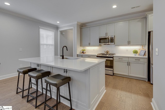 kitchen with visible vents, backsplash, gray cabinetry, appliances with stainless steel finishes, and a sink