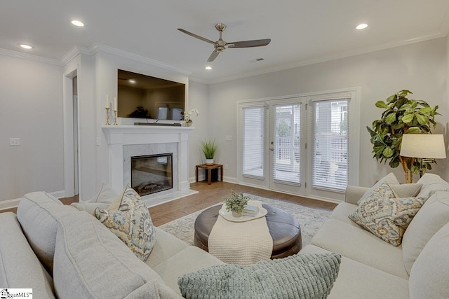 living area with baseboards, wood finished floors, a high end fireplace, and crown molding