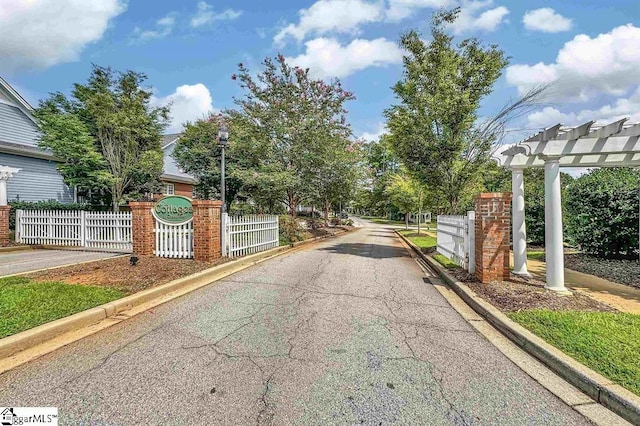 view of street with curbs, street lighting, and a gate