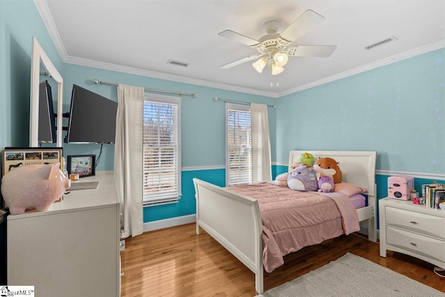 bedroom featuring ceiling fan, ornamental molding, wood finished floors, and visible vents