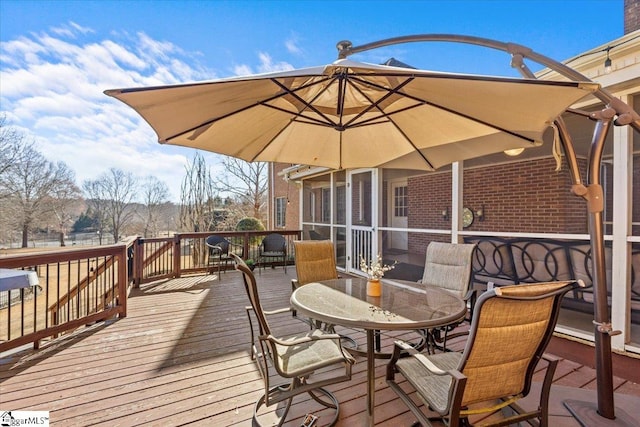 deck with outdoor dining space and a sunroom