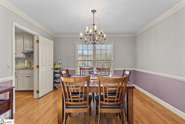 dining area featuring light wood-style flooring, a chandelier, baseboards, and ornamental molding