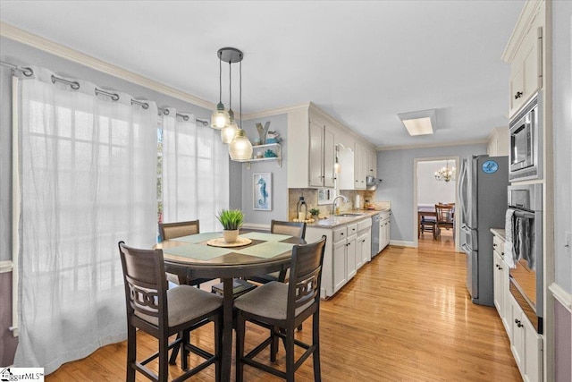 kitchen with light wood-style flooring, decorative backsplash, appliances with stainless steel finishes, white cabinetry, and a sink