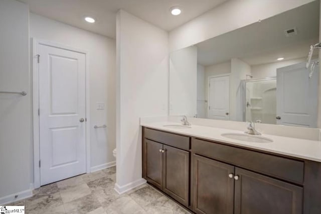 bathroom featuring double vanity, a stall shower, visible vents, and a sink