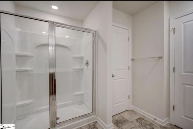 bathroom with a shower stall and baseboards