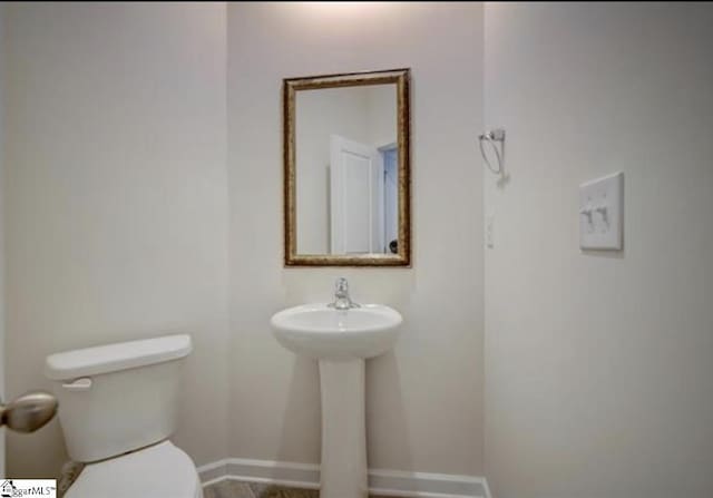 bathroom with baseboards and toilet