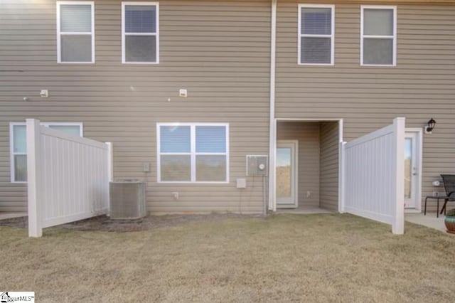 rear view of property with a lawn and central air condition unit