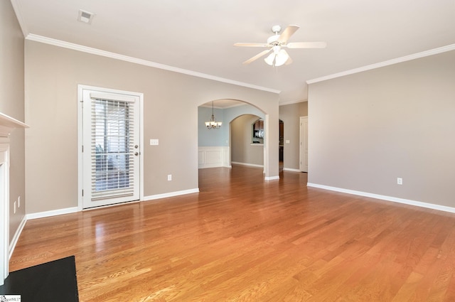 unfurnished living room with arched walkways, ornamental molding, ceiling fan with notable chandelier, and light wood-style floors