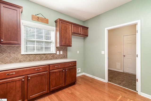 kitchen with light wood-style floors, baseboards, light countertops, and decorative backsplash