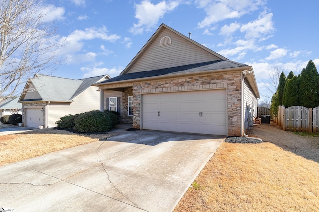 view of front of property featuring a garage, cooling unit, stone siding, and driveway