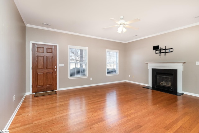 unfurnished living room featuring a glass covered fireplace, ceiling fan, baseboards, and wood finished floors